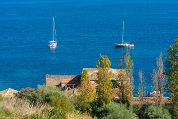Sailboats anchor in front of the famous tonnara of Scopello,  a former tuna factory and fishing...