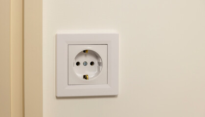 Electricity supply. Electric socket isolated on white wall. Renovated studio apartment, power background. Place for text. Focus on the outlet.