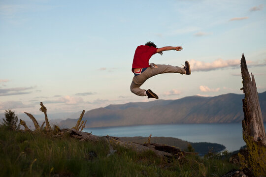 Young adult jumping over lake in   Idaho.
