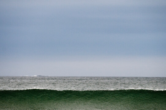 An ocean wave breaks along a beach.