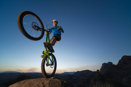A man performs trial bike standing on a rock at El Diente, Jalisco, Mexico.