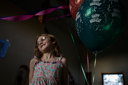 A young girl smiles while standing next to balloons during a birthday party celebrating her eighth birthday, in Breckenridge, Co