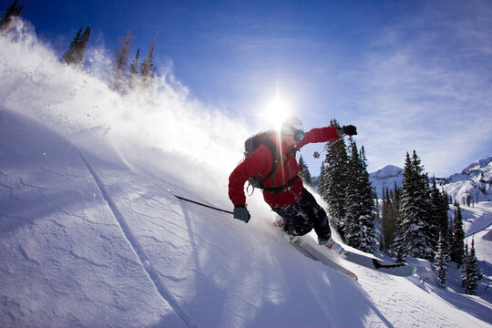 Male telemark skier in Alta, UT carving with blue skies in the background.