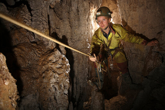 A young girl holds a rope in a cave