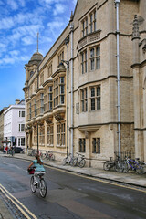 Fototapeta na wymiar Street with Oxford University building and pub, and cyclist on the road