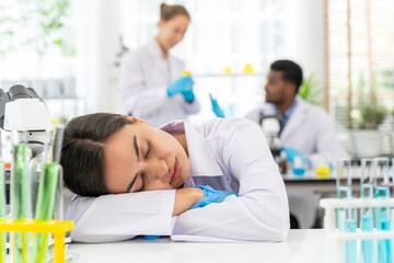 Young scientist female sleepy on table while working in laboratory