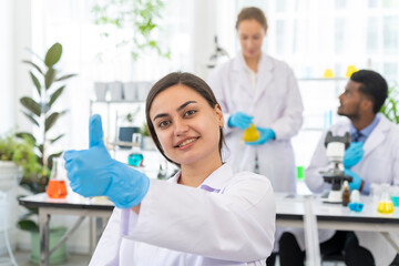 Young scientist female show thumb up  while working in laboratory