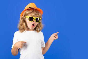 Young handsome kid pointing away on blue background. Excited kid boy on studio isolated background....