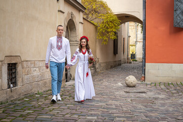 Portrait of a happy young couple in love, a family hugging, holding hands in the city of Lviv in traditional Ukrainian shirts, holding hands. Young people hug in the old town of Lviv