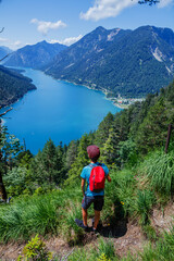 Hiker in the Alps. Boy backpacker tourist hiking at Lake. - 560879981
