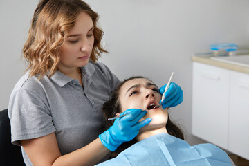 Dentist checking teeth of a female patient with dental mirror