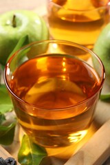 Glass of fresh apple juice on wooden tray, closeup