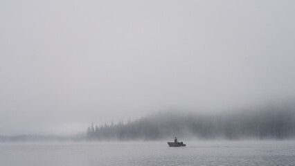 Early morning on the water a single fisherman going fishing in a small aluminum boat. 