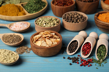 Many different spices on light blue wooden table