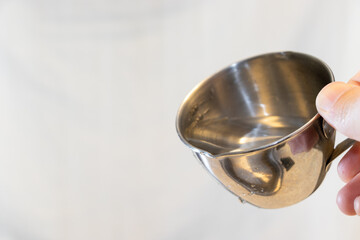 水が入った金属製のカップを傾ける