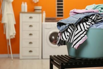 Laundry basket filled with clothes on bench in bathroom, closeup. Space for text