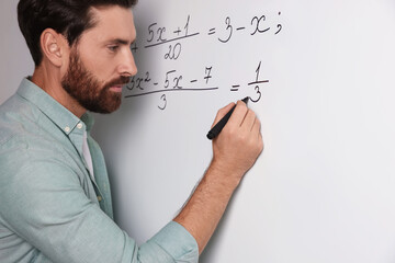 Mature teacher explaining mathematics at whiteboard in classroom, closeup