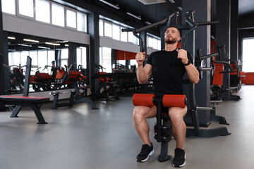 Naklejka na ściany i meble Man training with professional machine in gym