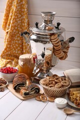 Traditional Russian samovar and treats on white wooden table