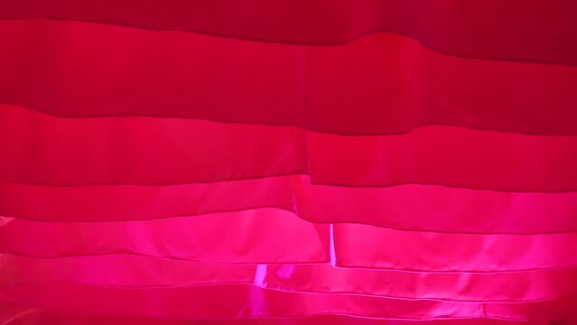 Light flowing red fabric imitating waves. The concept of lightness, female beauty, tenderness. Air show. Association with women's critical days.
