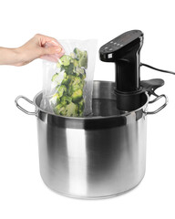 Woman putting vacuum packed broccoli into pot with sous vide cooker on white background, closeup....