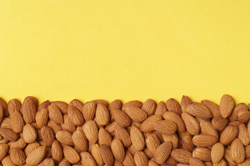 Delicious raw almonds on yellow background, flat lay. Space for text