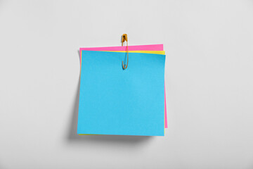 Paper notes attached with safety pin to white background, top view