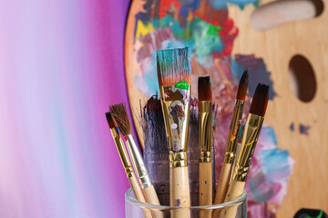 Fototapeta premium Brushes with colorful paints and wooden artist's palette. Space for text