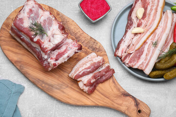 Tasty pork fatback with pickled cucumbers, garlic and dill on grey table, flat lay