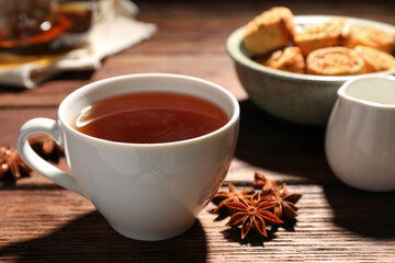 Cup of aromatic hot tea with anise stars on wooden table