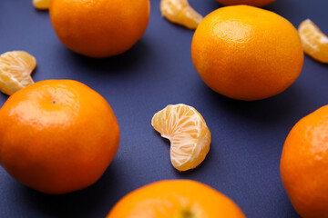 Fresh juicy tangerines and segments on blue table