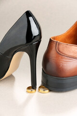 Woman's heel and man's shoe stepped on gold wedding rings against light gray background. Divorce...