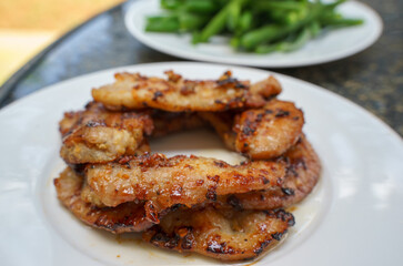 Pork belly is fried with oil. Before that it is well marinated with fish sauce, sugar, black pepper, chopped garlic. After frying for more than 10 minutes, serve with plain rice and boiled vegetables.