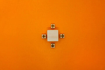 大きなウッドキューブに四方を向いた矢印のオレンジ色の背景