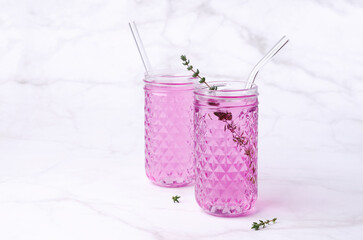 Pink drink with thyme in a glass