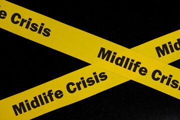 Midlife crisis caution and warning concept. Yellow barricade tape with word midlife crisis in dark black background.