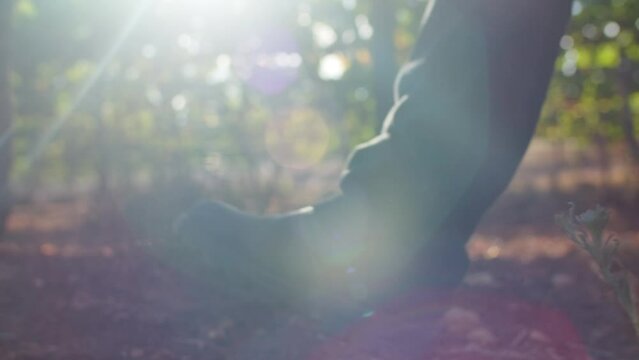 The shoes of a man walking on the soil of a vineyard in the morning. Handheld slow motion shot, low point-of-view.
