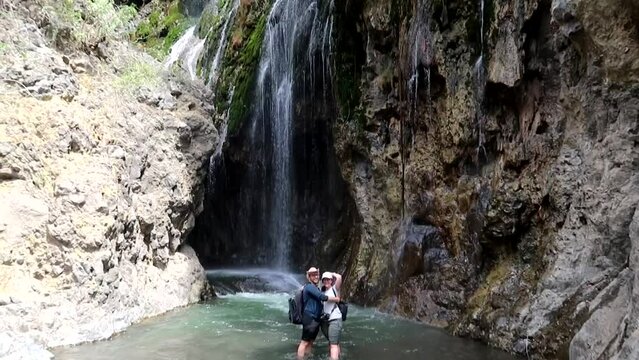 Couple pose for photos under a beautiful waterfall, Lake Natron, Tanzania