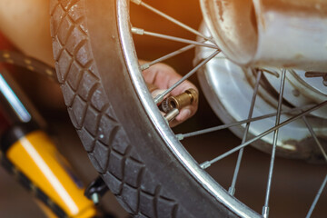 Hands of man check inflator pressure and inflates tire on motorcycle with bicycle floor pump. Man...