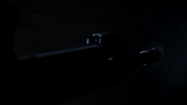 Barrel of AR-15 assault rifle firing multiple times in a dark room