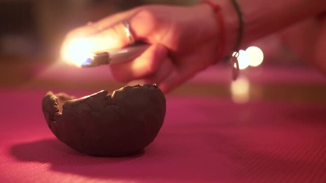 Close up of woman lighting an earthen candle clay pot with a lighter for relaxing