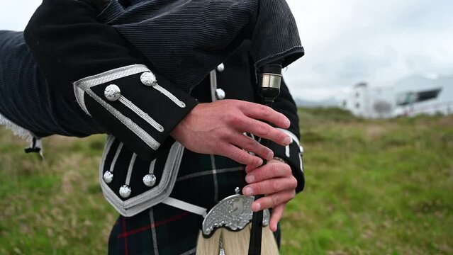 Close-up shot of a bagpiper playing a song in his traditional Scottish kilt