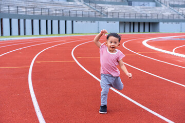 Fototapeta premium A boy in a sportswear and sneakers runs on the running track at the stadium outdoors.