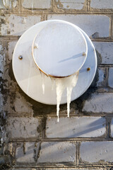 Ventilation of an old gas boiler with icicles. Gas heating in winter.