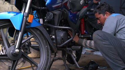 Young man repairing or preparing a motorbike for a new season after winter time, basic motorcycle maintenance - Powered by Adobe