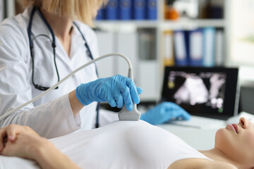 Doctor makes breast ultrasound to young woman in clinic closeup