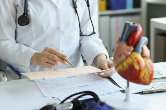 Cardiologist doctor holding and reading an ecg paper report of patient with heart disease