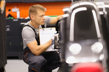 Male mechanic inspects motorcycle in workshop. Motorcycle repair