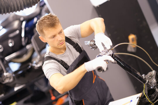 Auto mechanic repairs motorcycle fork in workshop