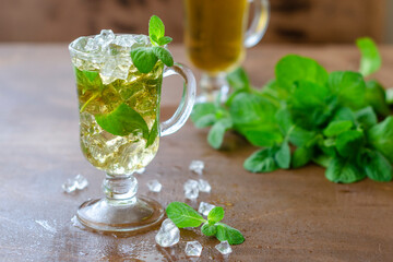 mint cocktail in a beautiful glass with ice and fresh mint leaves on a gray background, alcoholic refreshing drink